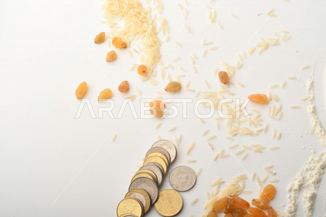 مجموعة من الأرز والزبيب والقمح والطحين والعملات المعدنية على خلفية بيضاء