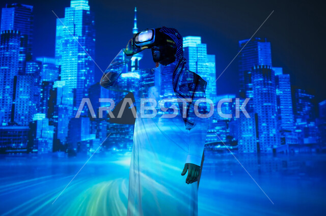 الوقوف أمام الأبراج المضيئة باللون الأزرق، رؤية سعودية مستقبلية ٢٠٣٠، الأبراج وناطحات السحاب المميزة في المملكة العربية السعودية ليلاً، شاب عربي خليجي سعودي يرتدي الثوب التقليدي والشماغ ينظر من خلال نظارات الفي ار، النمو والتطور العمراني في العاصمة