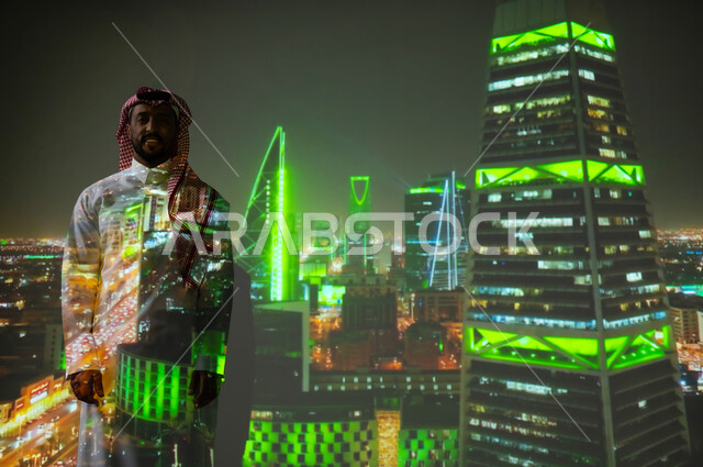 الفن الهندسي المعماري المتميز، ايماءات السعادة والفخر، معالم سياحية مشهورة، شاب عربي خليجي سعودي يرتدي الثوب التقليدي يقف أمام الأبراج وناطحات السحاب المضيئة باللون الأخضر ليلا ينظرإلى الكاميرا، النمو والتقدم والتطور العمراني في المملكة العريبة السعودية