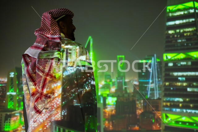 Famous tourist attractions, distinguished architectural art, a young Saudi Gulf Arab wearing a traditional dress standing in front of towers and skyscrapers illuminated in green at night on Saudi National Day, September 23, growth, progress and urban development in the Kingdom of Saudi Arabia