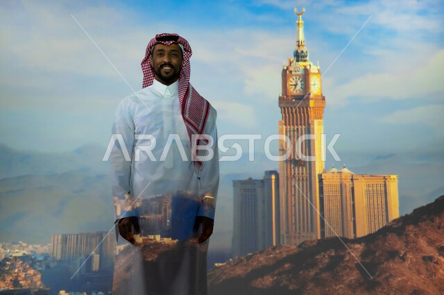 ايماءات السعادة والبهجة، المعالم الاسلامية الدينية المقدسة في السعودية, الفن الهندسي المعماري للمنشآت والمباني، شاب عربي خليجي سعودي يرتدي الثوب التقليدي يقف أمام برج الساعة الملكي في مكة المكرمة في وضح النهار ينظر إلى الكاميرا، الأبراج وناطحات السحاب في المملكة العربية السعودية