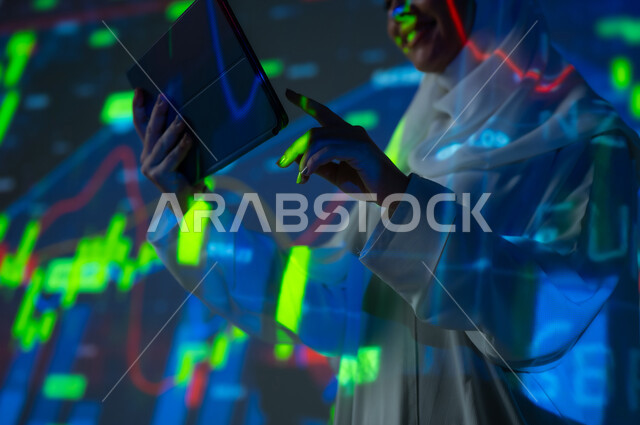 صعود و هبوط أسهم البورصة, مفهوم التحليل المالي وفرص الاستثمار, سوق الأوراق المالية, امرأة عربية خليجية سعودية محجبة تقف أمام شاشة مليئة بالأرقام و الإحصائيات تستخدم جهاز التابلت اللوحي, خلفية هولوجرامية ثلاثية الأبعاد