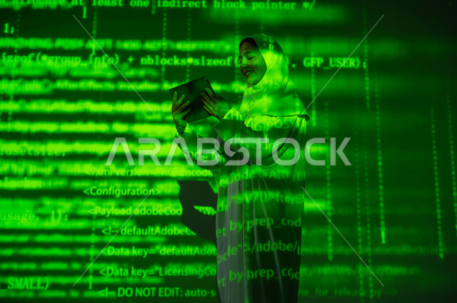 مفهوم التطور العلمي و التقني، دمج العلم بالتكنولوجيا، استخدام التقنيات الحديثة المتطورة، إمرأة عربية خليجية سعودية محجبة تستخدم جهاز التابلت المحمول, خلفية هولوجرامية ثلاثية الأبعاد باللون الاخضر