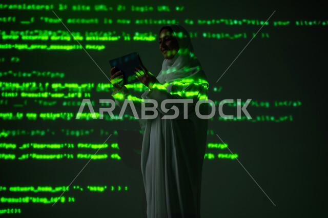 دمج العلم بالتكنولوجيا، استخدام التقنيات الحديثة المتطورة، إمرأة عربية خليجية سعودية محجبة تستخدم جهاز التابلت المحمول, التطور العلمي و التقني، خلفية هولوجرامية ثلاثية الأبعاد باللون الاخضر