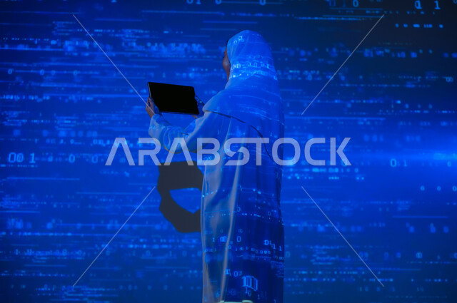 Using advanced modern technologies, a picture from behind of a smiling, veiled Saudi Gulf Arab woman displaying a blank black screen on the tablet, scientific and technical development in the Kingdom, numbers and calculations in mathematics, integrating science with technology, background laws and mathematical algorithms