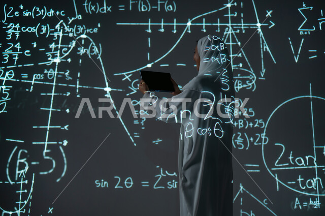 Integrating science with technology, using advanced modern technologies, a picture from the back of a smiling Saudi Arabian Gulf woman, veiled and wearing an abaya, displaying a blank black screen on the tablet, scientific and technical development in the Kingdom, numbers and calculations in mathematics, background laws, mathematical algorithms