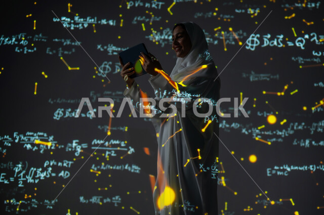 أرقام وحسابات في مادة الرياضيات، دمج العلم بالتكنولوجيا، استخدام التقنيات الحديثة المتطورة، صورة من الخلف لإمرأة عربية خليجية سعودية مبتسمة محجبة ترتدي العباءة تمسك جهاز التابلت وتنظر إليه, التطور العلمي و التقني في المملكة، خلفية قوانين خوارزميات رياضية