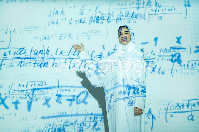 التطور العلمي و التقني في المملكة، أرقام وحسابات في مادة الرياضيات، امرأة عربية خليجية سعودية مبتسمة محجبة ترتدي العباءة تنظر الى الكاميرا بإيماءات السعادة والسرور وتشير بيدها الى المعادلات الحسابية, دمج العلم بالتكنولوجيا، خلفية قوانين خوارزميات رياضية