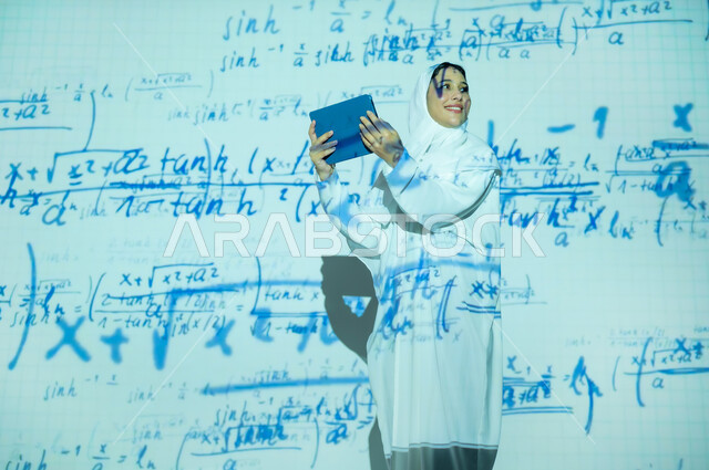 استخدام التقنيات الحديثة المتطورة، التطور العلمي و التقني في المملكة، امرأة عربية خليجية سعودية مبتسمة محجبة ترتدي العباءة تمسك جهاز التابلت وتنظر لشيء ما, أرقام وحسابات في مادة الرياضيات، دمج العلم بالتكنولوجيا، خلفية قوانين خوارزميات رياضية