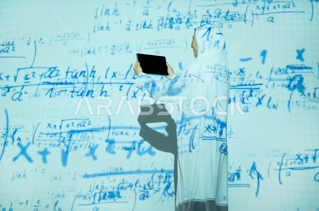 التطور العلمي و التقني في المملكة، صورة من الخلف لإمرأة عربية خليجية سعودية مبتسمة محجبة ترتدي العباءة تعرض شاشة سوداء فارغة عبر التابلت, أرقام وحسابات في مادة الرياضيات، دمج العلم بالتكنولوجيا، استخدام التقنيات الحديثة المتطورة، خلفية قوانين خوارزميات رياضية