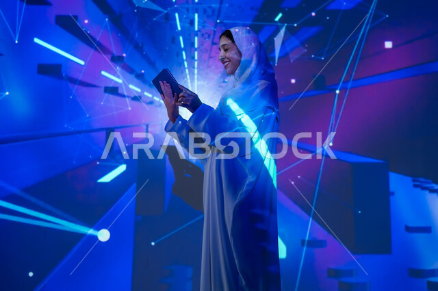 Using advanced modern technologies, promoting the concept of digital and technological development in Saudi society, a smiling Saudi Arabian Gulf woman, veiled and wearing an abaya, holding a tablet, a background of various colors using holographic technology
