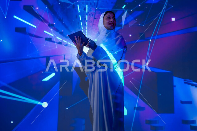 Promoting the concept of digital and technological development in Saudi society, a smiling Saudi Gulf Arab woman, veiled, wearing an abaya, holding a tablet and looking at something, using advanced modern technologies, a background of various colors with holographic technology