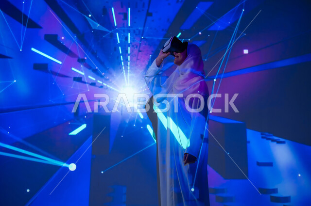 محاكاة الواقع الافتراضي والخيالي واستخدام التكنولوجيا الحديثة المتطورة ، امرأة عربية خليجية سعودية مبتسمة محجبة ترتدي العباءة تضع نظارات في آر تشير بإصبع السبابة الى شيء، النقر على شاشة هولوجرامية مضيئة ثلاثية الأبعاد