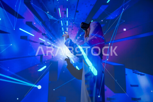 استخدام التكنولوجيا الحديثة المتطورة ومحاكاة الواقع الافتراضي والخيالي، امرأة عربية خليجية سعودية مبتسمة محجبة ترتدي العباءة تضع نظارات في آر تشير بإصبع السبابة الى شيء، النقر على شاشة هولوجرامية مضيئة ثلاثية الأبعاد