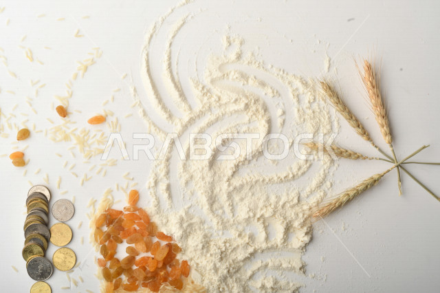 مجموعة من الأرز والزبيب والقمح والطحين والعملات المعدنية على خلفية بيضاء