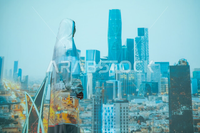 تطوير وتحديث التصاميم الهندسية المعمارية، أماكن ومعالم مشهورة في المملكة، صورة من الخلف لإمرأة عربية خليجية سعودية محجبة ترتدي العباءة تنظر الى الأبراج ، المباني العالية وناطحات السحاب في مركز الملك عبد الله المالي ( كافد ) في الرياض