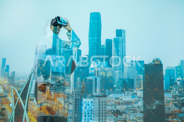 أماكن ومعالم مشهورة في المملكة، استخدام التقنيات المتطورة، امرأة عربية خليجية سعودية مبتسمة محجبة ترتدي العباءة تضع نظارات الواقع الافتراضي، المباني العالية وناطحات السحاب في مركز الملك عبد الله المالي ( كافد ) في الرياض, تطوير التصاميم الهندسية المعمارية