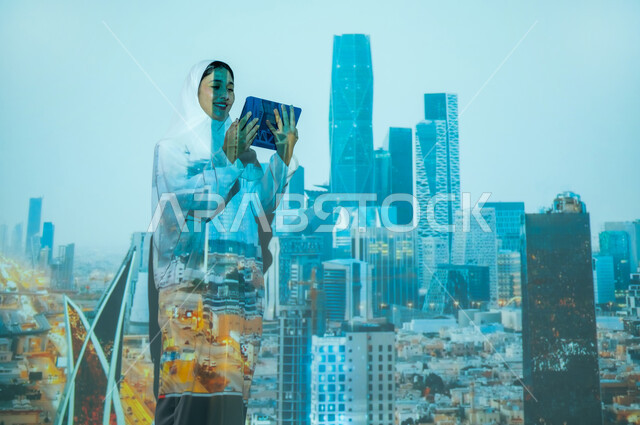 تطوير التصاميم الهندسية المعمارية، امرأة عربية خليجية سعودية مبتسمة محجبة ترتدي العباءة تمسك بيديها جهاز التابلت، استخدام التقنيات الحديثة، المباني العالية وناطحات السحاب في مركز الملك عبد الله المالي ( كافد ) في مدينة الرياض, أماكن ومعالم مشهورة في المملكة