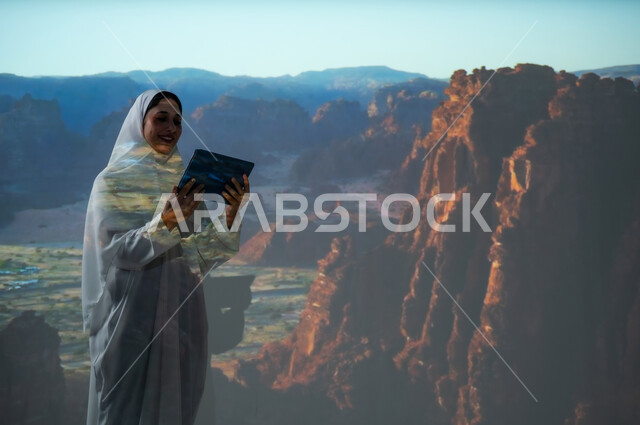 أماكن ومعالم سياحية تاريخية أثرية في محافظة العلا، امرأة عربية خليجية سعودية مبتسمة محجبة ترتدي العباءة تمسك بيديها جهاز التابلت، استخدام التقنيات الحديثة المتطورة، القمم والمرتفعات الجبلية، التكوينات الصخرية في المناطق الصحراوية