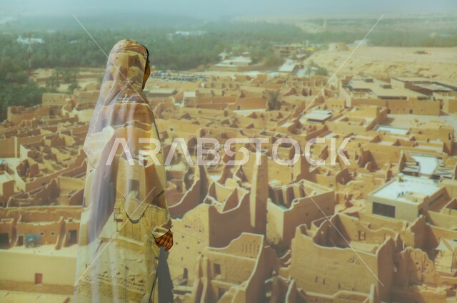 الفن الهندسي المعماري على الطراز القديم، المباني والبيوت الأثرية الطينية في الدرعية، صورة من الخلف لإمرأة عربية خليجية سعودية محجبة ترتدي العباءة تنظر الى المنازل، أماكن ومعالم سياحية شعبية تراثية، جذب واستقطاب السائحين من مختف البلدان