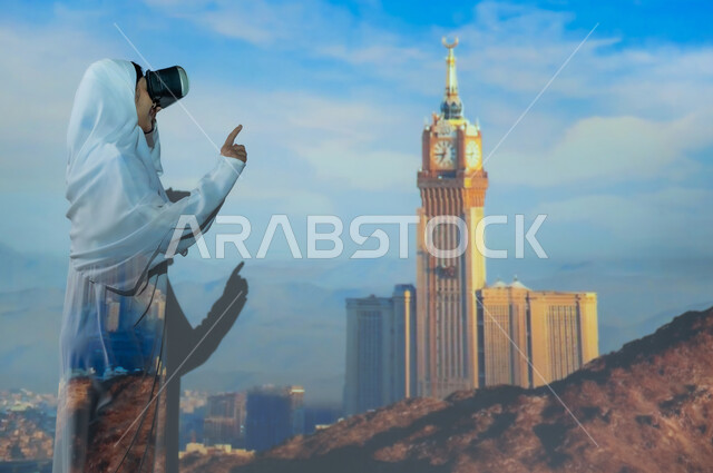 معالم وأماكن إسلامية دينية في المملكة، صورة من الجانب لإمرأة عربية خليجية سعودية مبتسمة محجبة ترتدي العباءة البيضاء تضع نظارة الواقع الافتراضي وترفع إصبع السبابة، استخدام التكنولوجيا الحديثة والمتطورة، خلفية برج الساعة وناطحات السحاب المحيطة به في مكة المكرمة