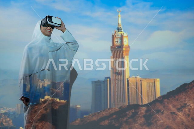 استخدام التكنولوجيا الحديثة والمتطورة، امرأة عربية خليجية سعودية مبتسمة محجبة ترتدي العباءة البيضاء تضع نظارة الواقع الافتراضي، معالم وأماكن إسلامية دينية، الفن الهندسي المعماري الحديث في البناء, خلفية برج الساعة وناطحات السحاب المحيطة به في مكة المكرمة
