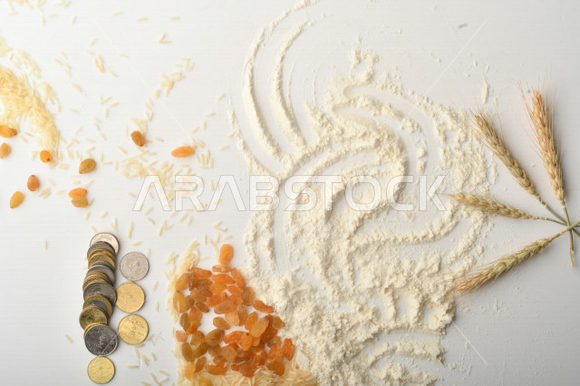 مجموعة من الأرز والزبيب والقمح والطحين والعملات المعدنية على خلفية بيضاء