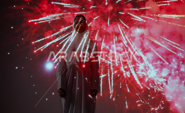 احتفالات ومهرجانات في المملكة، الاستمتاع بالألعاب النارية في الأعياد والمناسبات، أنشطة ترفيهية وفعاليات احتفالية، إمرأة عربية خليجية سعودية مبتسمة ترتدي العباءة والحجاب تنظر إلى المفرقعات، الاحتفال باليوم الوطني السعودي