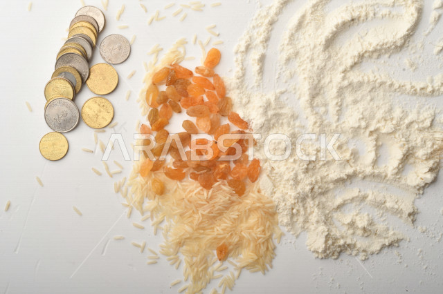 مجموعة من الأرز والزبيب والقمح والطحين والعملات المعدنية على خلفية بيضاء