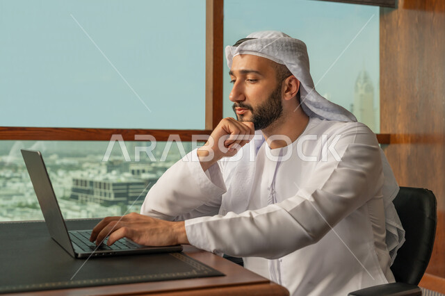 Gestures of seriousness and focus, office jobs and professions, close-up side view of smiling Arab Gulf Emirati businessman wearing white kandura and ghutra using laptop in company headquarters, integrating work with technology and technology