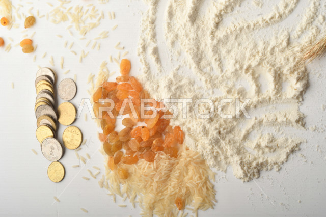 مجموعة من الأرز والزبيب والقمح والطحين والعملات المعدنية على خلفية بيضاء