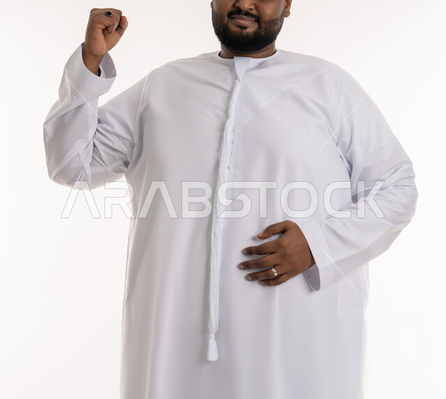 Insistence on healthy diet, finding solution to health problems, losing fat and calories, close-up portrait of a plump Emirati Gulf Arab man wearing Emirati kandura raising his hand with gestures of strength and determination, suffering from excess weight and obesity, white background