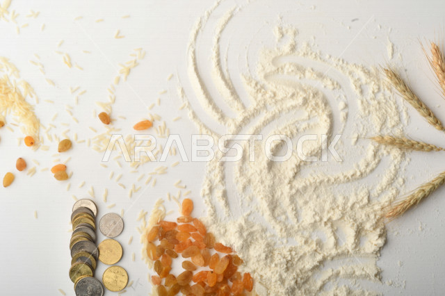 مجموعة من الأرز والزبيب والقمح والطحين والعملات المعدنية على خلفية بيضاء