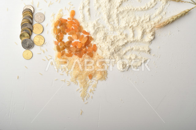 مجموعة من الأرز والزبيب والقمح والطحين والعملات المعدنية على خلفية بيضاء