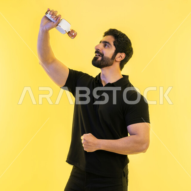 إيماءات وتعابير الاندماج والتفاعل مع الموسيقا، تقديم العروضات المسرحية، ممارسة موهبة الغناء، الاستمتاع بأداء المواهب الصوتية، بورتريه من الجانب لشاب عربي خليجي اماراتي يرتدي الزي الكاجوال يمسك بيده المايكروفون، تسجيل مقطع صوتي غنائي، خلفية صفراء