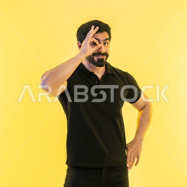 رؤية الاشياء البعيدة، حب المغامرة والاستكشاف، التخطيط المستقبلي للأهداف والطموحات، بورتريه لشاب عربي خليجي اماراتي يرتدي الزي الكاجوال يضع يده على عينه على شكل منظار، خلفية صفراء