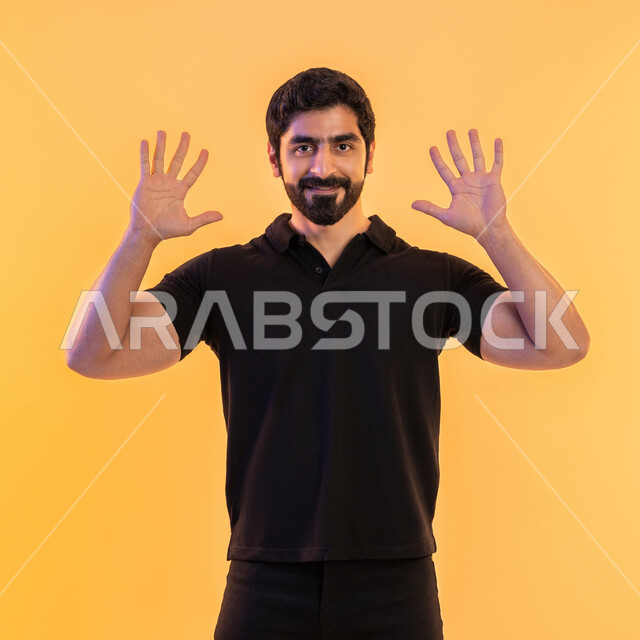 الإستفهام حول موضوع معين, بورتريه لرجل عربي اماراتي يرتدي الزي الكاجوال يرفع يديه نحو الأعلى بإيماءات عدم المعرفة, التساؤل والإستغراب والاستفسار عن أمر ما، الغموض وعدم الوضوح، خلفية صفراء