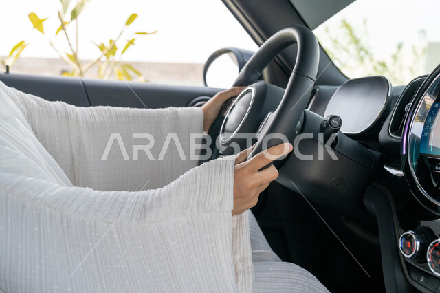 إتقان مهارة القيادة عند النساء الخليجيات, مفهوم الاستقلال واعتماد الأنثى على نفسها, صورة مقربة لسيدة عربية خليجية إماراتية تمسك المقود بيديها، شابة سعودية ترتدي العباءة تجلس في سيارتها, الانتباه للطريق واتباع قواعد السلامة, حرية المرأة العربية في القيادة