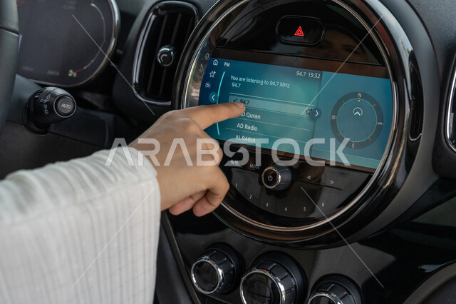 مفهوم الاستقلال والحرية للمرأة العربية، صورة مقربة ليد سيدة عربية خليجية إماراتية تقوم بالتحكم بشيء ما عبر لمس الشاشة أمامها، اعتماد المرأة على نفسها في التنقل والمواصلات، شابة سعودية تقود في الطرق والشوارع العامة، حرية القيادة للمرأة الخليجية