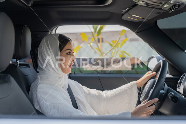حرية القيادة للمرأة الخليجية، تطبيق مفهوم الأمان والحماية، الاعتماد على النفس عند المرأة العربية في التنقل و المواصلات، إمرأه عربية خليجية إماراتية محجبة تجلس في سيارتها، سيده سعودية تضع حزام الأمان وتقود بتركيز، التقيد بالأنظمة والقوانين وتنفيذها