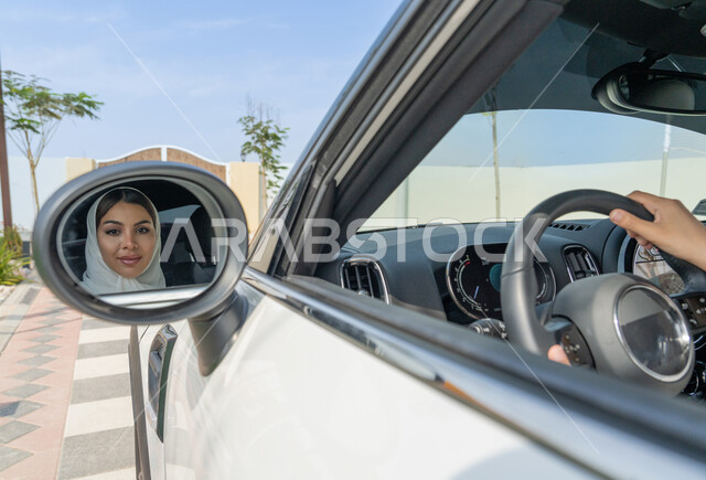 قيادة الأنثى للسيارات في شوارع الخليج العربي, اعتماد المرأة على نفسها في التنقل و المواصلات، مفهوم الاستقلال والاعتماد على النفس، صورة لانعكاس وجه مرأه عربية خليجية إماراتيه محجبة في المرآة، حرية القيادة للمرأة العربية، سيده سعودية تمسك المقود بيديها