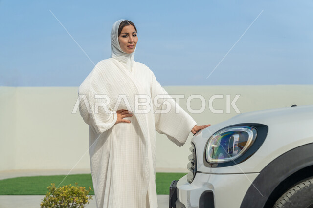 حرية القيادة للمرأة العربية، اعتماد المرأة على نفسها في التنقل و المواصلات، إمرأه عربية خليجية إماراتية محجبة تقف بجانب سيارتها، سيدة سعودية ترتدي العباءة البيضاء, مفهوم الاستقلال والاعتماد على النفس عند الأنثى الخليجية