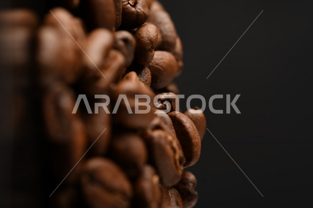 تناثر حبوب البن المحمصة على خلفية داكنة , حبوب بن القهوة البنية العضوية .