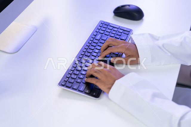 الإجابة على أسئلة العملاء، مفهوم العمل في مجال خدمة الزبائن، اعداد وتقديم البرامج الإذاعية، بورتريه مقرب لأيدي موظف عربي خليجي اماراتي يرتدي الزي التقليدي يجلس في المكتب يعمل على جهاز الحاسوب، دمج التقنيات الحديثة في الحياة العملية