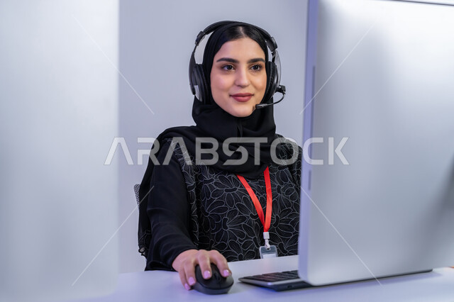 ايماءات البهجة والسرور، مساهمة النساء في الوظائف المكتبية، مفهوم العمل في مجال خدمة الزبائن، دمج التقنيات الحديثة المتطورة بالحياة العملية، الإجابة على أسئلة العملاء، بورتريه مقرب لموظفة عربية خليجية اماراتية تجلس في المكتب تقوم باداء عملها، خلفية رمادية
