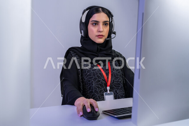 تقديم البرامج الإذاعية، مساهمة النساء في الوظائف المكتبية، مفهوم العمل في مجال خدمة الزبائن، دمج التقنيات الحديثة المتطورة بالحياة  العملية، بورتريه مقرب لموظفة عربية خليجية اماراتية تجلس في المكتب تعمل على جهاز الحاسوب لأداء المهام اليومية، خلفية رمادية