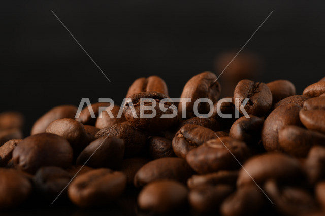 تناثر حبوب البن المحمصة على خلفية داكنة , حبوب بن القهوة البنية العضوية .