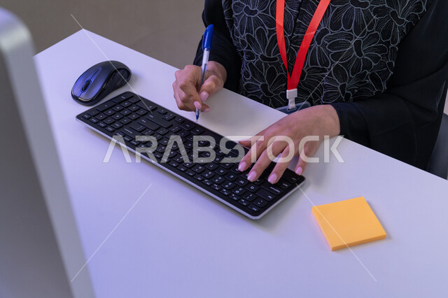 Source of work in the field of customer service, using modern devices, preparing and presenting radio programs, women's participation in office jobs, answering customers' questions, close-up portrait of the hands of an Arab Gulf Emirati female employee sitting in the office working on the computer to perform daily tasks