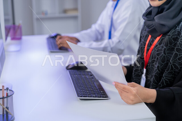 مساهمة النساء في الوظائف المكتبية، مفهوم العمل في مجال خدمة الزبائن، استخدام الأجهزة التقنية الحديثة، الإجابة على أسئلة العملاء، بورتريه مقرب لموظفان عربيين خليجيين اماراتيين يجلسان في المكتب يقومان بالتعاون والتشارك في اداء المهام