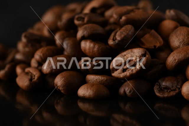 تناثر حبوب البن المحمصة على خلفية داكنة , حبوب بن القهوة البنية العضوية .